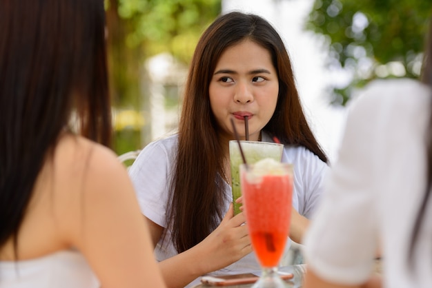 Três jovens mulheres asiáticas como amigas sentadas juntas em um café ao ar livre