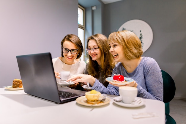 Três jovens mulheres bonitas usam laptop pc na cafeteria