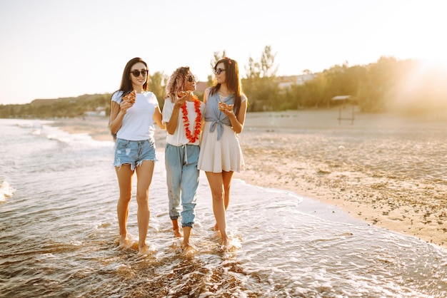 Três jovens passando tempo juntos na praia fazendo piquenique comendo pizza