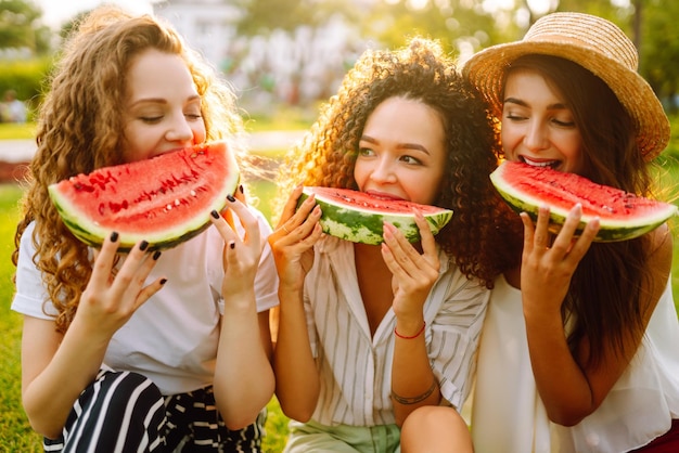 Três jovens se divertem juntos e comendo melancia em dia quente de verão