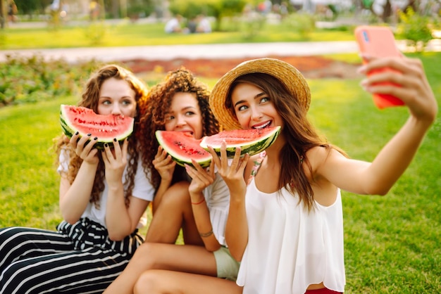 Três jovens se divertem juntos e comendo melancia em dia quente de verão