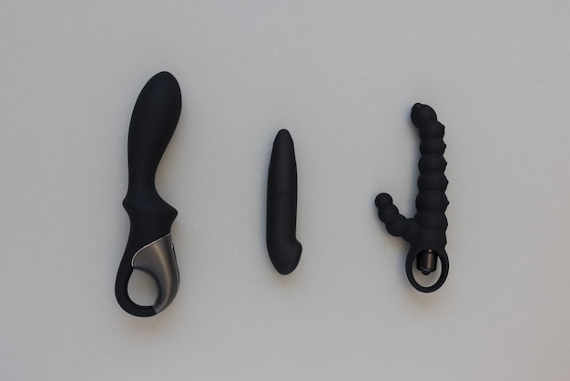 Tres juguetes sexuales negros para hombre y mujer adultos sobre fondo gris consolador vibrador trasero en forma de conejo
