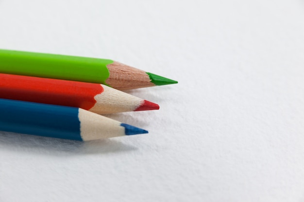 Tres lápices de colores sobre fondo blanco.