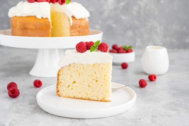 Tres leches Kuchen mit Schlagsahne und frischen Himbeeren auf einem grauen Betonhintergrund