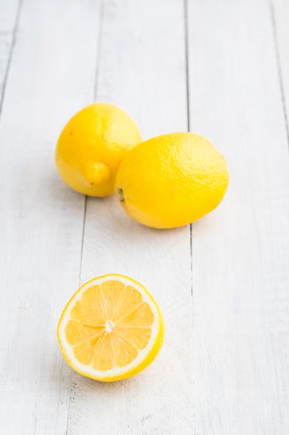 Tres limones en la mesa de madera blanca.