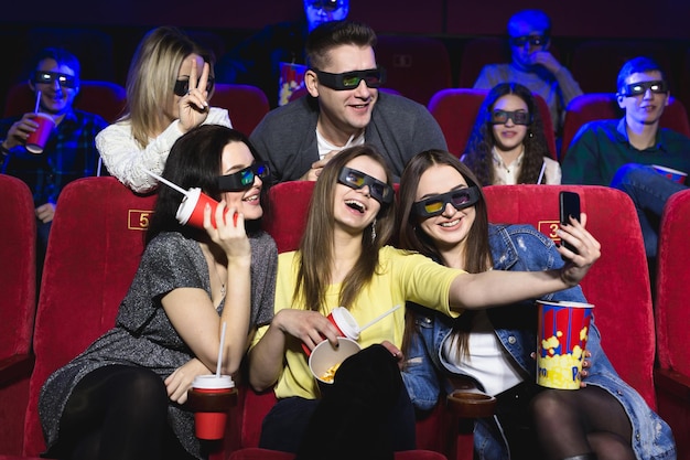 Três lindas amigas rindo alegremente fazendo uma selfie juntas durante um filme