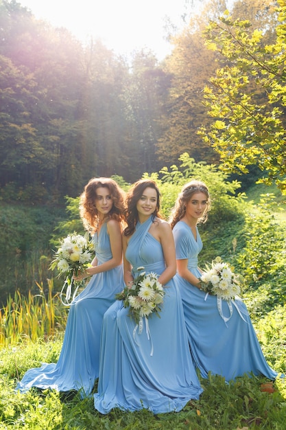 Três lindas damas de honra no parque no dia do casamento