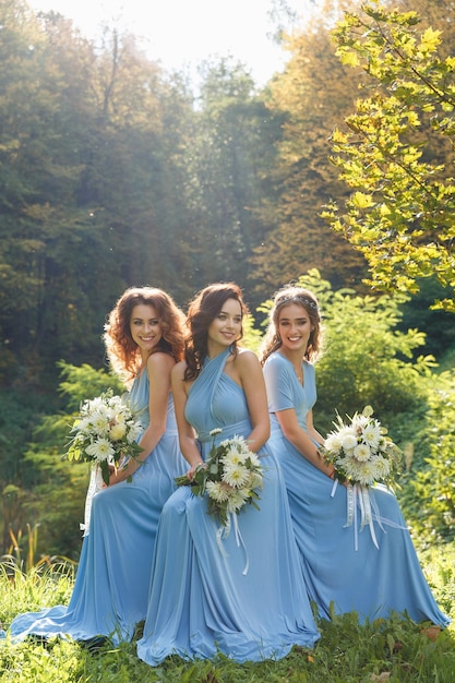 Três lindas damas de honra no parque no dia do casamento