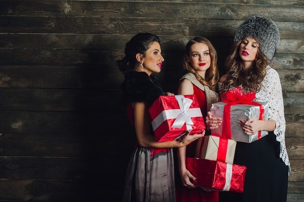 Três lindas meninas com presentes de natal em um fundo de madeira