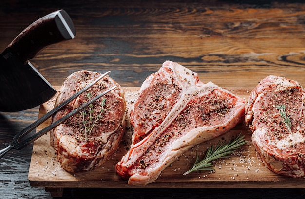 Três lindos bifes de carne Angus pretos marmorizados crus aromatizados com uma mistura de pimenta moída e prontos para cozinhar e servir em um fundo escuro de madeira