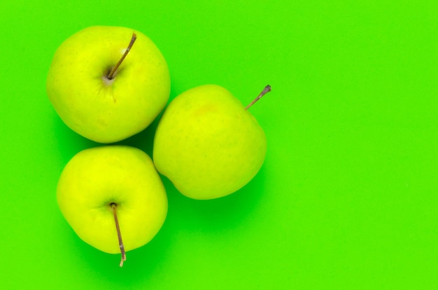 Foto três maçãs frescas verdes sobre fundo verde brilhante