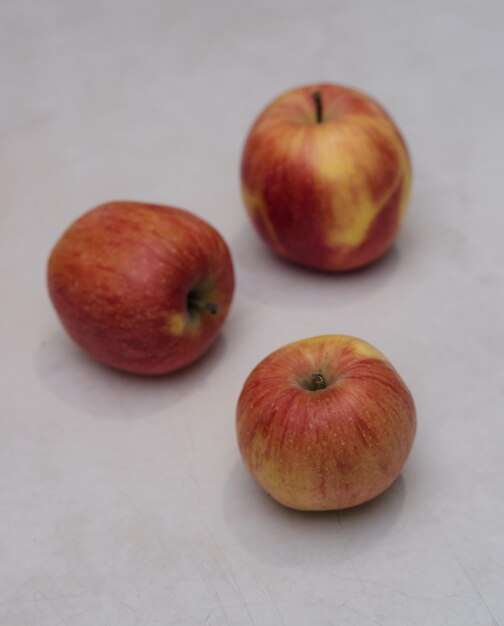 Três maçãs vermelhas em uma mesa de madeira clara