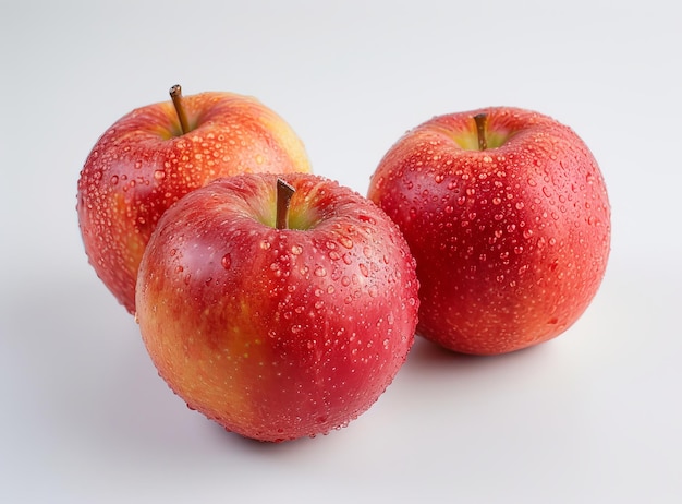 Três maçãs vermelhas frescas maduras com gotas de água isoladas em um fundo branco