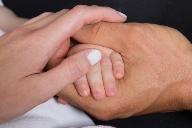 Tres manos de la familia, bebé, hija, madre y padre. Concepto de unidad, apoyo, protección y felicidad.