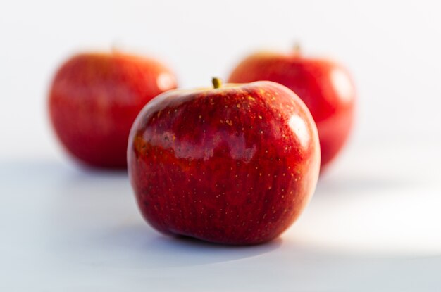 Tres manzanas rojas sobre blanco