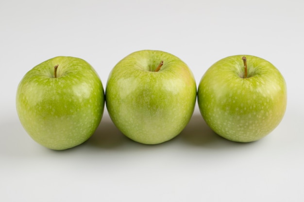 Tres manzanas verdes frescas colocadas en el cuadro blanco.