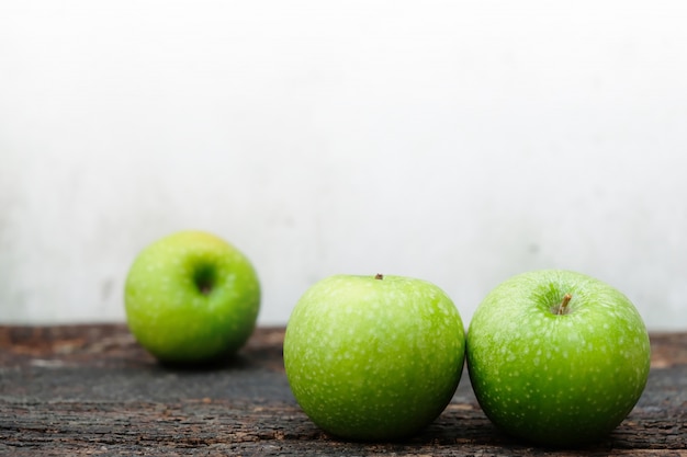 Tres manzanas verdes frescas colocadas en la madera