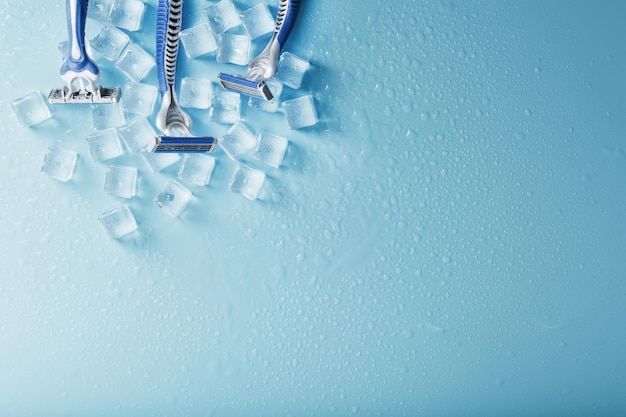 Tres máquinas de afeitar sobre un fondo azul helado con hielo El concepto de limpieza