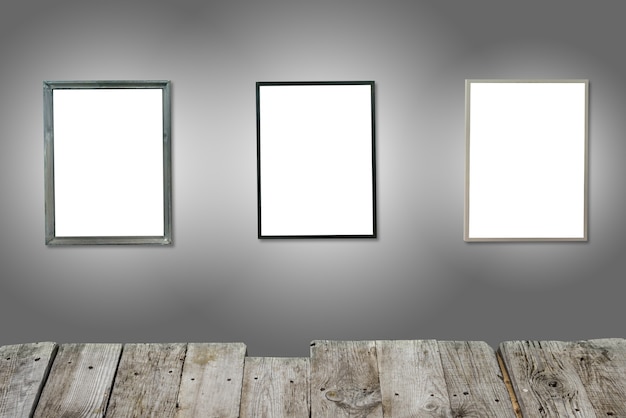 Tres marcos de madera blancos aislados en la pared gris con escritorio de madera