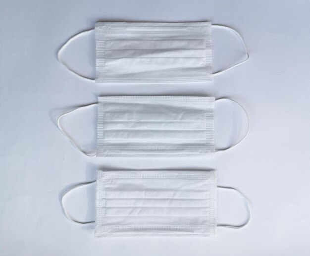Três máscaras médicas brancas em uma vista superior de fundo branco Máscara médica para proteção
