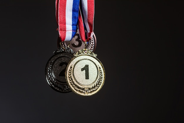 Tres medallas de oro, plata y bronce colgadas sobre un fondo oscuro. Concepto de deportes y victoria.