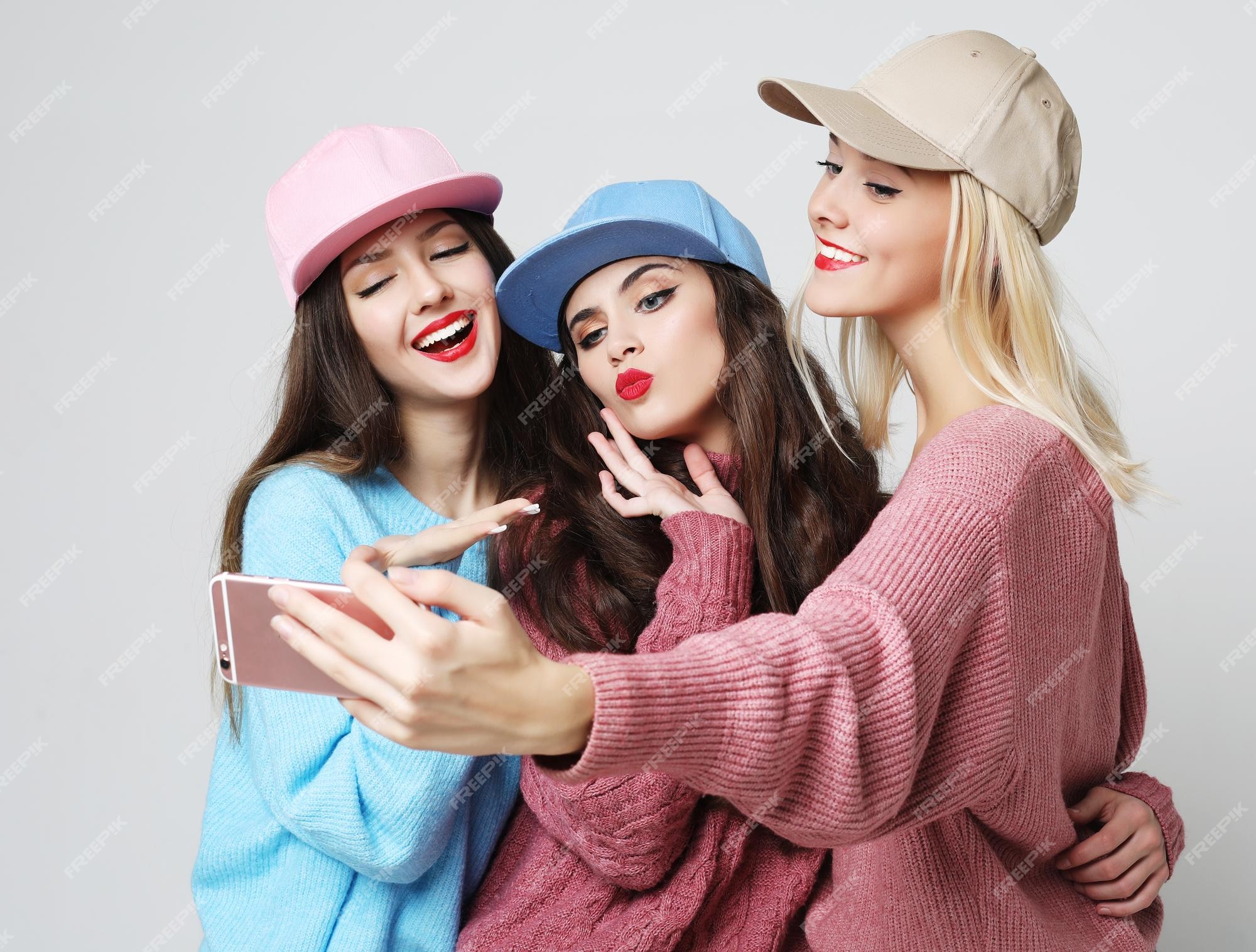 Tres mejores amigas felices con suéteres y haciendo selfie en teléfono inteligente Foto Premium