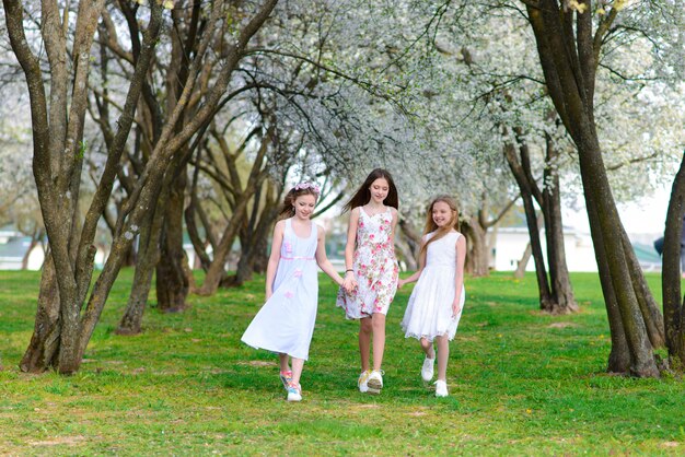 Três meninas adoráveis em vestidos no jardim