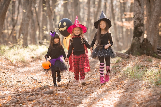 Três meninas em fantasias de bruxa riem evocam caminhada pela floresta de outono conceito de halloween