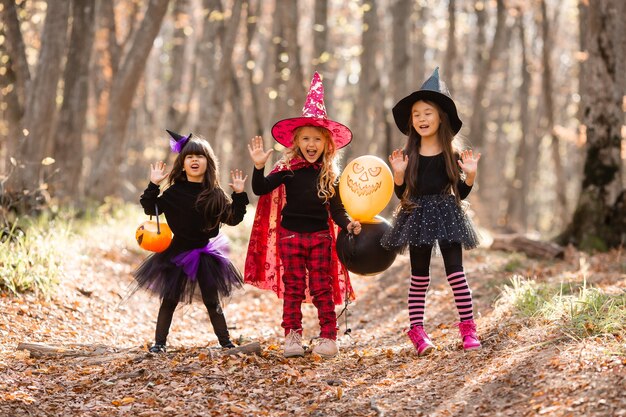 Três meninas em fantasias de bruxa riem evocam caminhada pela floresta de outono conceito de halloween