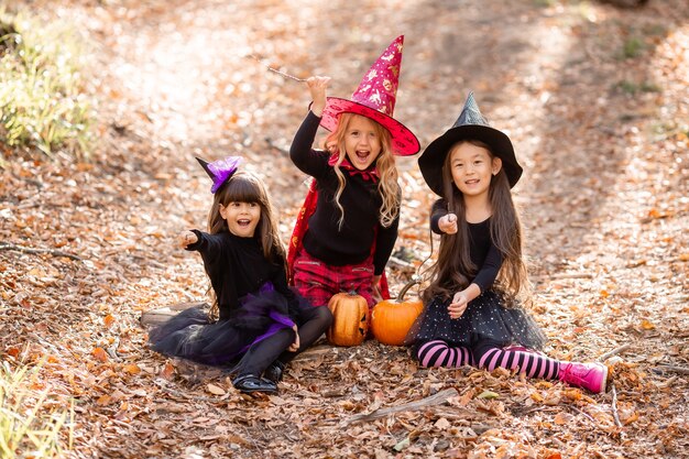 Três meninas em fantasias de bruxa riem evocam caminhada pela floresta de outono conceito de halloween