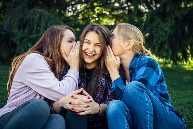 três meninas sentados e conversando ao ar livre