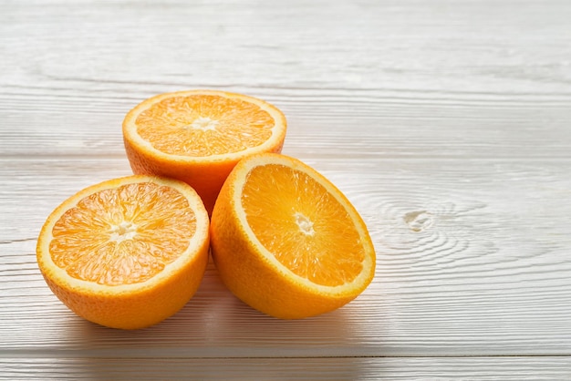 Tres mitades de jugosas naranjas sobre una mesa de madera blanca