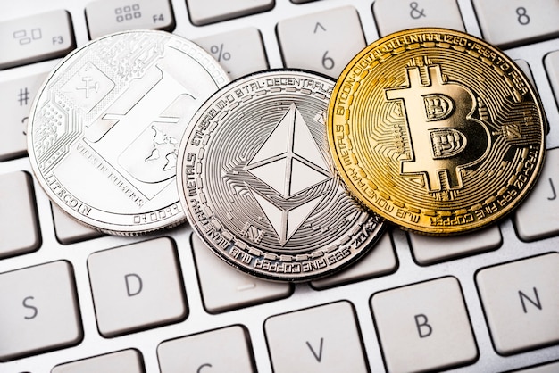 Tres monedas de metal físicas: Litcoin, Ethereum y Bitcoin en el teclado. Conceptos de criptomonedas.