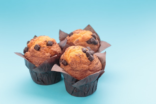 Foto três muffins de chocolate em um fundo azul.