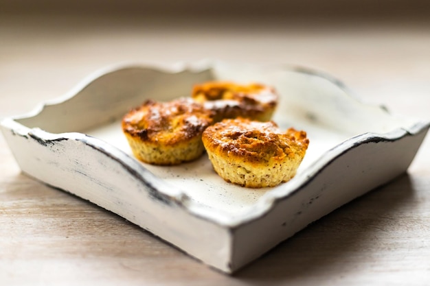 Foto três muffins de cupcake de páscoa caseiros recém-assados na bandeja vintage de madeira branca no fundo da mesa