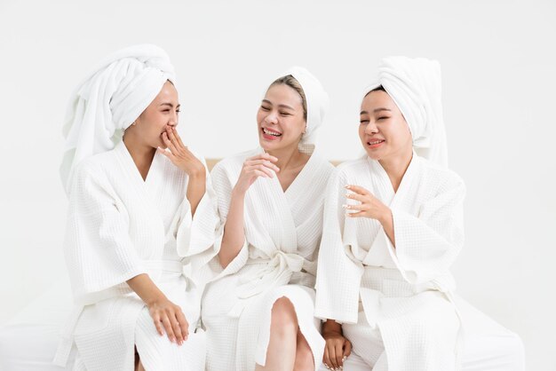 Foto tres mujeres asiáticas jóvenes en túnicas de baño toallas en las cabezas disfrutan de charlar amigas