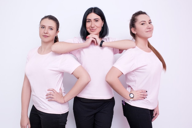 Tres mujeres con camisetas blancas. Jóvenes amigos, publicidad en ropa, campaña de promoción, azafatas sonrientes, concepto de equipo amigable