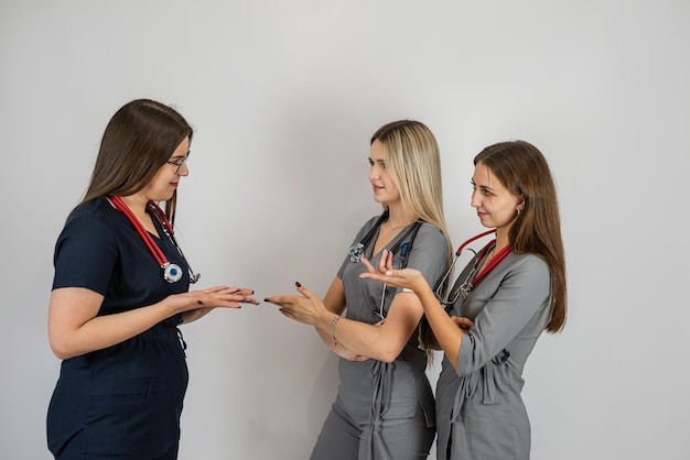Tres mujeres doctores usan uniforme con estetoscopio posando en una toma de estudio aislada