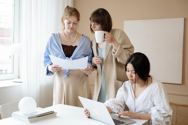 tres mujeres están trabajando en una computadora portátil y una de ellas tiene un papel