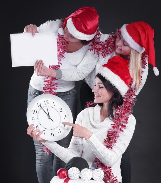 Tres mujeres felices disfrazadas de Papá Noel con reloj y Chris