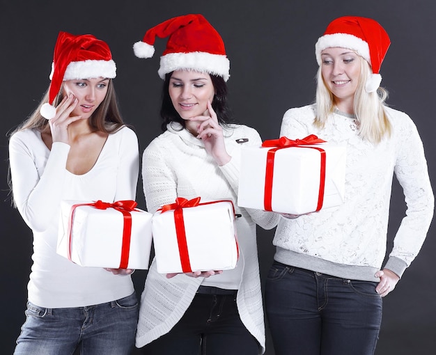 Tres mujeres jóvenes disfrazadas de Santa Claus con tienda de Navidad