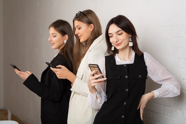 tres mujeres jóvenes con teléfonos móviles