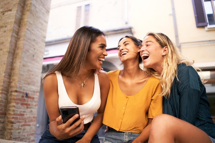 Foto tres mujeres multirraciales que usan teléfonos móviles al aire libre jóvenes y redes sociales