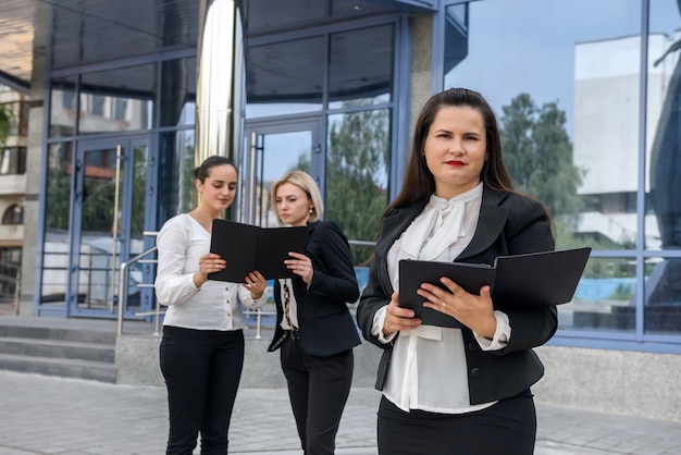 Tres mujeres de negocios exitosas de pie frente a la entrada central de la oficina