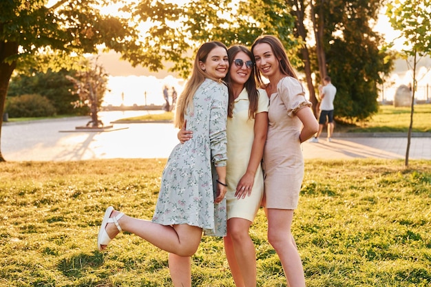 Tres mujeres de pie juntas en el parque de otoño Hermoso sol