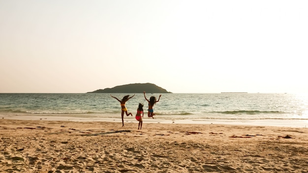 Tres mujeres sexy saltando juntos en la playa.