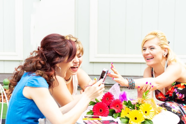 Tres mujeres sonrientes en una mesa en un café de verano