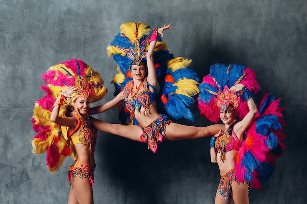 Tres mujeres en traje de cabaret con plumaje de plumas de colores.