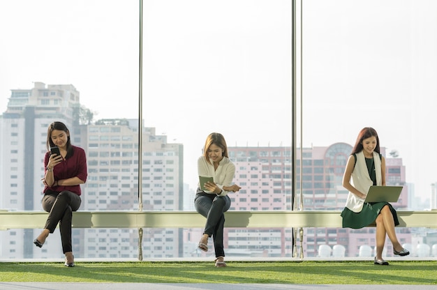 tres mujeres usan redes sociales cada equipo de tecnología en la moderna oficina creativa