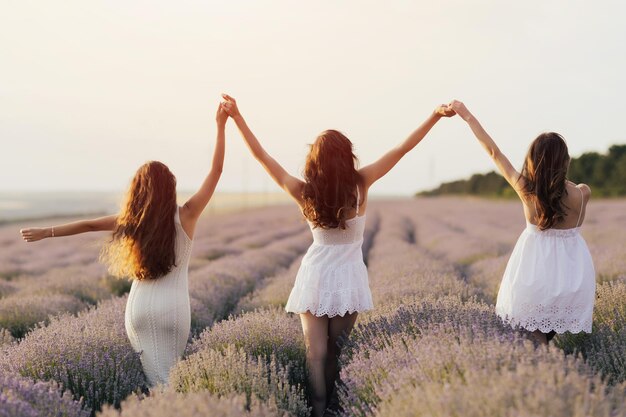 Tres mujeres vestidas de blanco caminan en un campo de lavanda